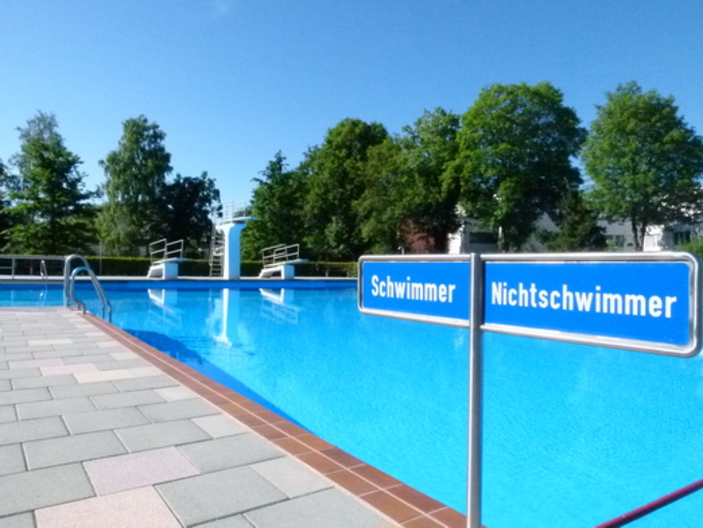 Hintergrund Schwimmbecken im Vordergrund ein Schild mit Schwimmer und Nichtschwimmer 