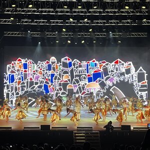 Im Vordergrund Bühne mit Tänzer im Hintergrund ein Bühnenbild 